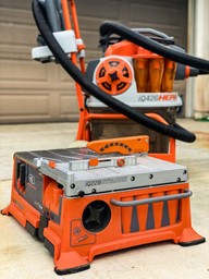 Orange masonry saw with black handles on a work surface