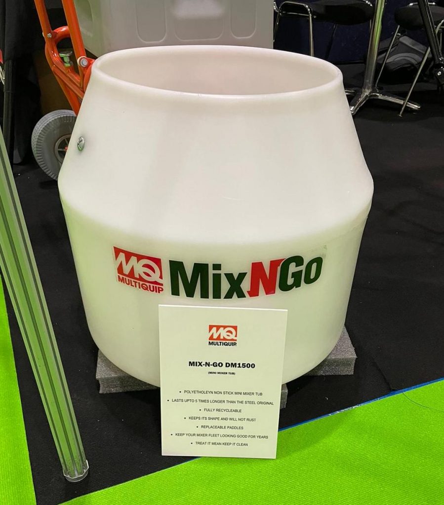 Multiquip Mix N Go portable drum mixer displayed at an event, featuring a white drum and a product information sign.