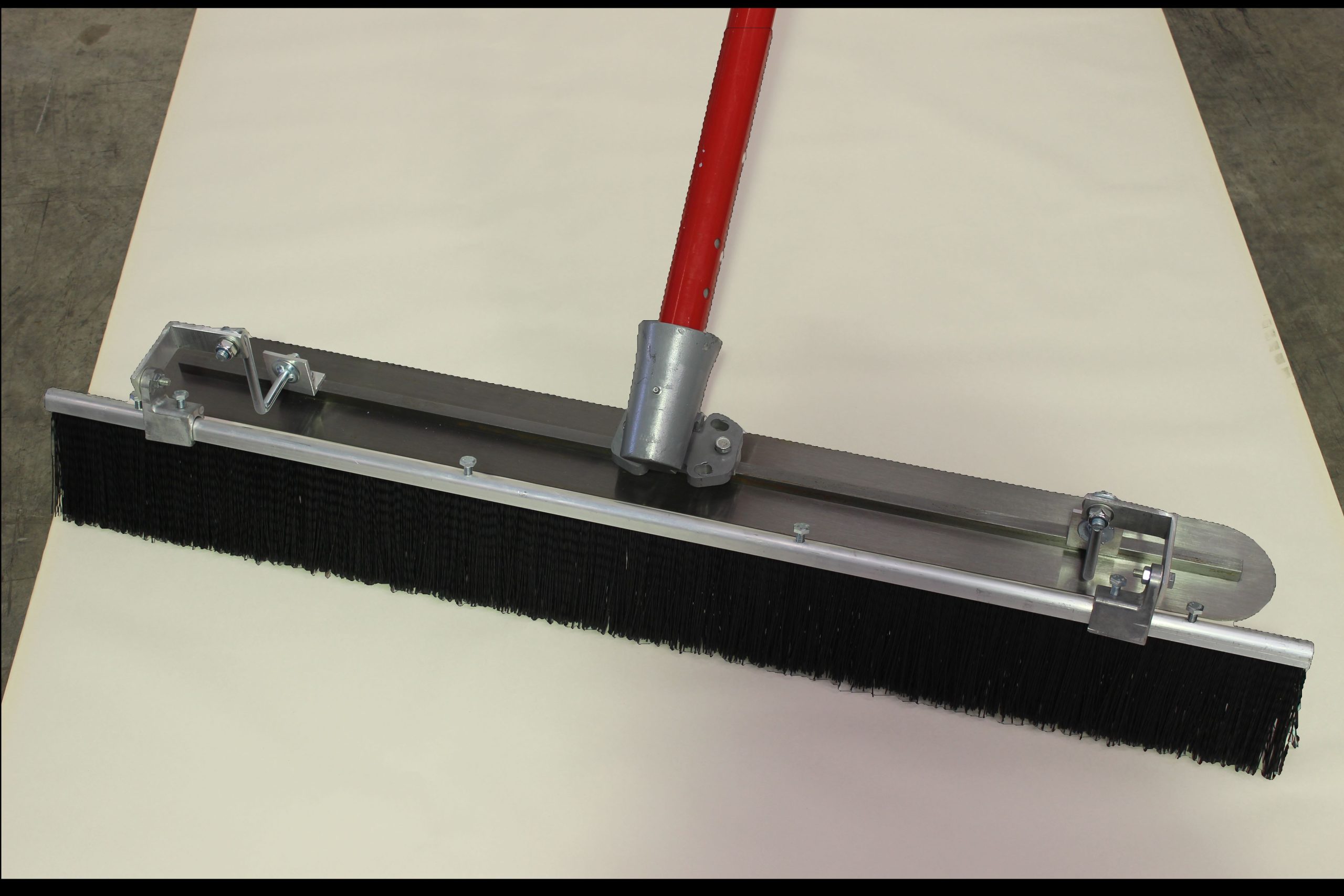 Fresno broom with red handle and black bristles, mounted on a metal frame for concrete finishing.